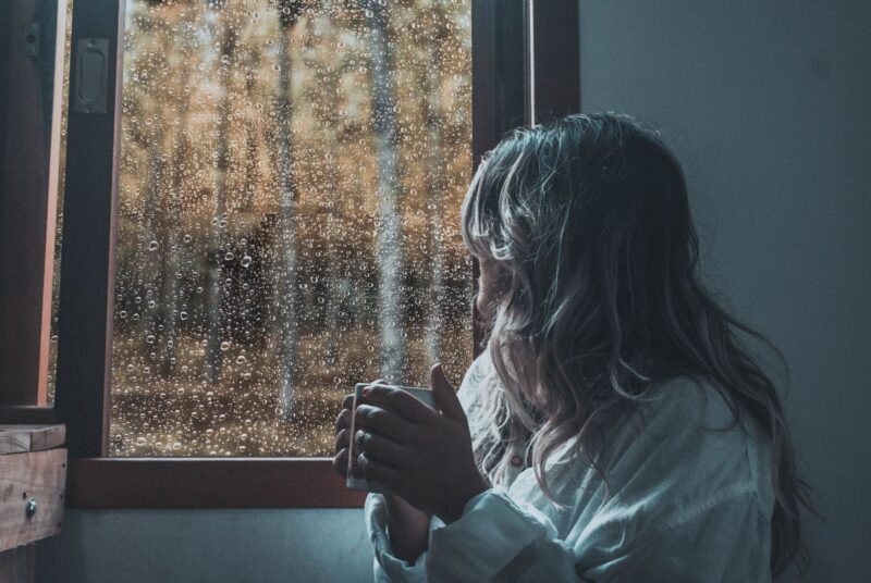 Person schaut nachdenklich aus dem Fenster